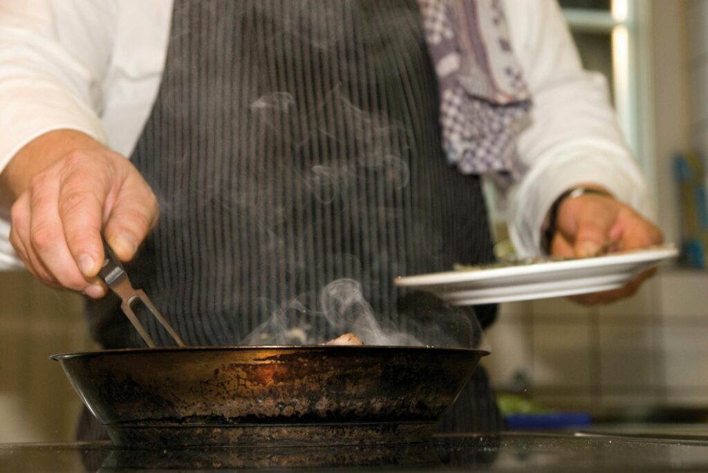 a chef works on a stainless steel coooktop